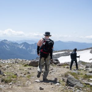 Couple hiking Skyline Trail in summer. Snow on the side of the trail. Mt Rainier National Park. Washington State.